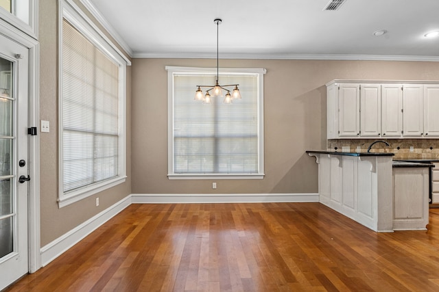 unfurnished dining area with hardwood / wood-style flooring, a chandelier, and crown molding