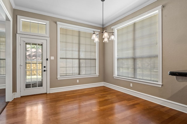 unfurnished dining area with hardwood / wood-style flooring, an inviting chandelier, and crown molding