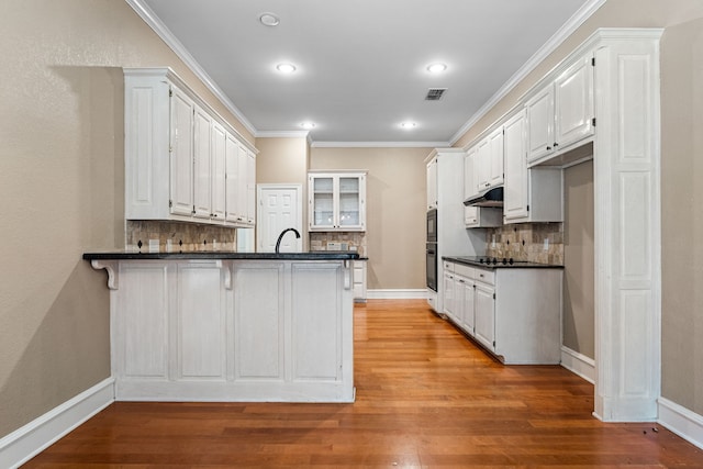 kitchen featuring white cabinets, kitchen peninsula, decorative backsplash, and light wood-type flooring