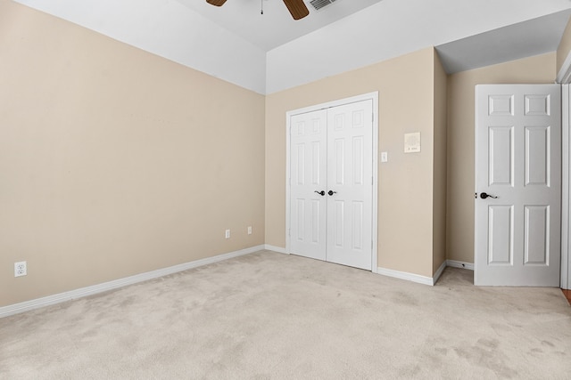 unfurnished bedroom featuring light colored carpet, ceiling fan, vaulted ceiling, and a closet