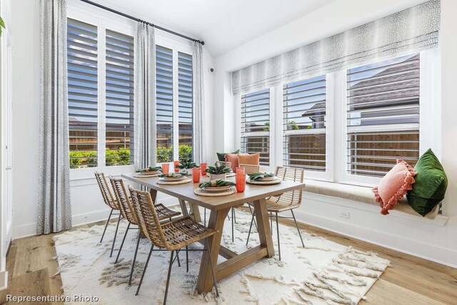 dining room with light hardwood / wood-style flooring and lofted ceiling