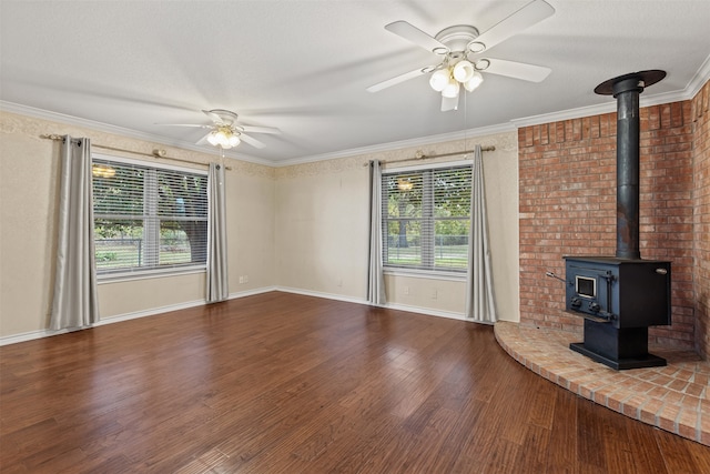 unfurnished living room featuring hardwood / wood-style floors, ceiling fan, a wood stove, and ornamental molding