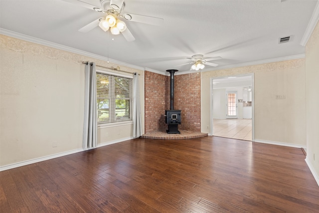 unfurnished living room featuring a wood stove, hardwood / wood-style flooring, and a healthy amount of sunlight