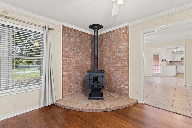 interior details featuring ornamental molding, a wood stove, ceiling fan, and wood-type flooring