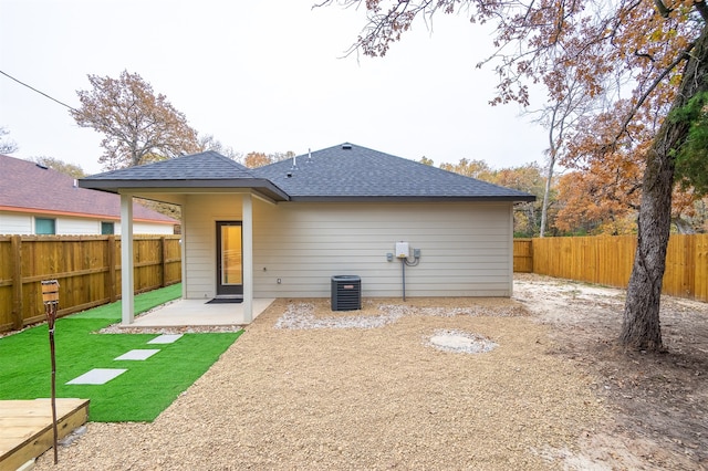 rear view of house featuring a lawn, central AC unit, and a patio