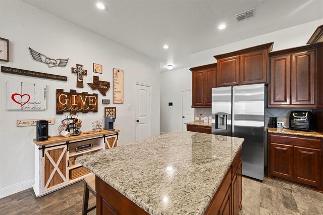 kitchen with light stone counters, decorative backsplash, stainless steel appliances, and premium range hood