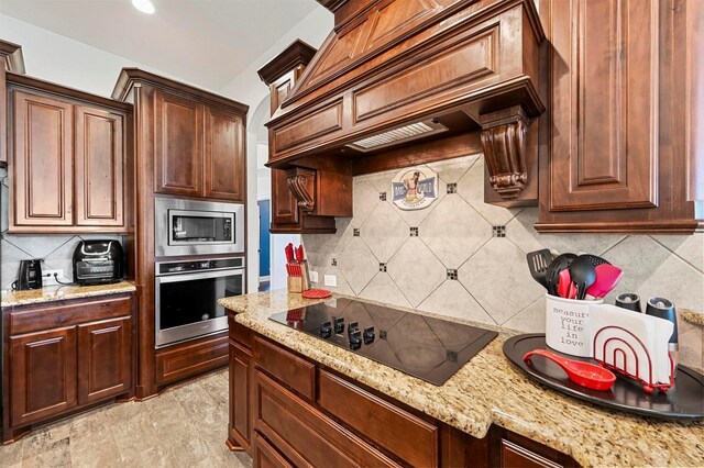 kitchen with premium range hood, backsplash, light stone counters, ornamental molding, and black electric cooktop