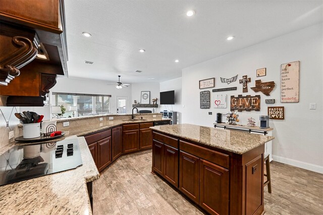 kitchen featuring sink, ceiling fan, light stone counters, ornamental molding, and a textured ceiling