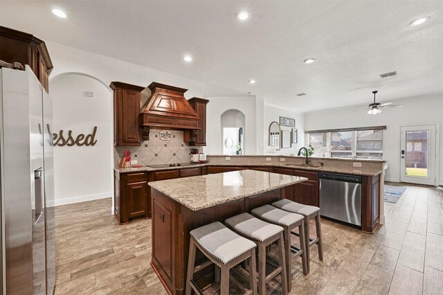 kitchen featuring a breakfast bar, dishwasher, sink, custom range hood, and black electric cooktop