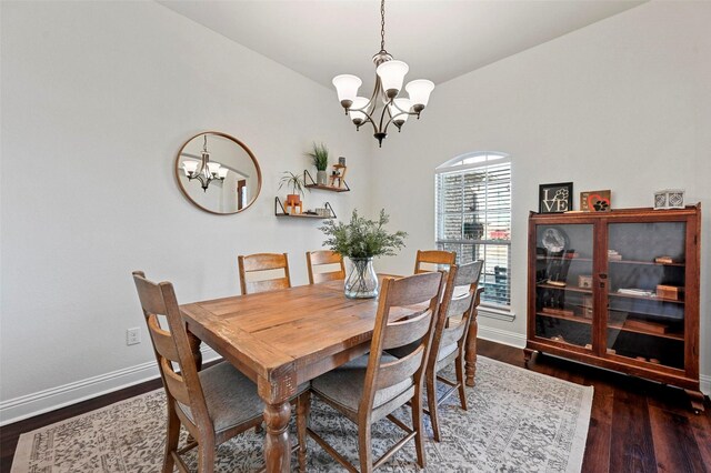 dining area featuring dark wood-type flooring and an inviting chandelier