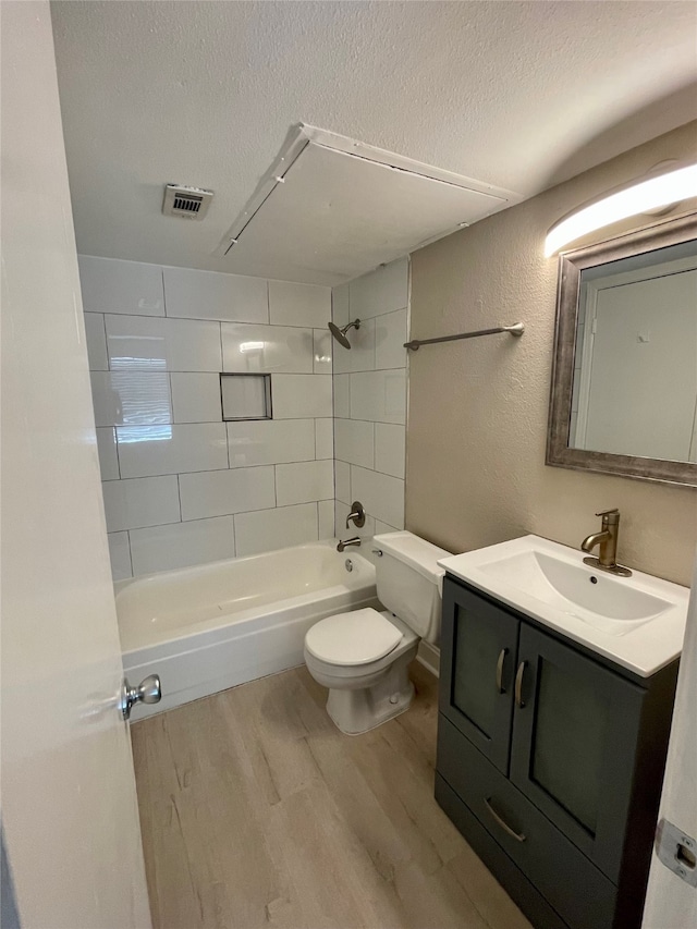 full bathroom with tiled shower / bath combo, vanity, wood-type flooring, and a textured ceiling