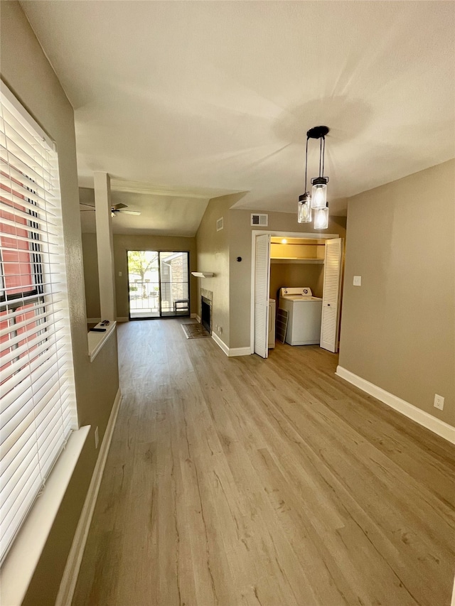 unfurnished living room with light hardwood / wood-style floors, ceiling fan, and washer / dryer