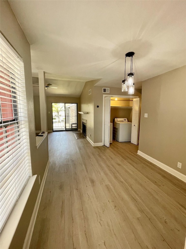 4748 Old Bent Tree Ln Unit 1104, Dallas, TX 75287 - unfurnished living room with washer / dryer, wood finished floors, baseboards, a fireplace, and vaulted ceiling