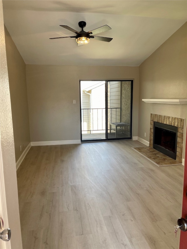 unfurnished living room featuring a brick fireplace, light wood-type flooring, ceiling fan, and vaulted ceiling