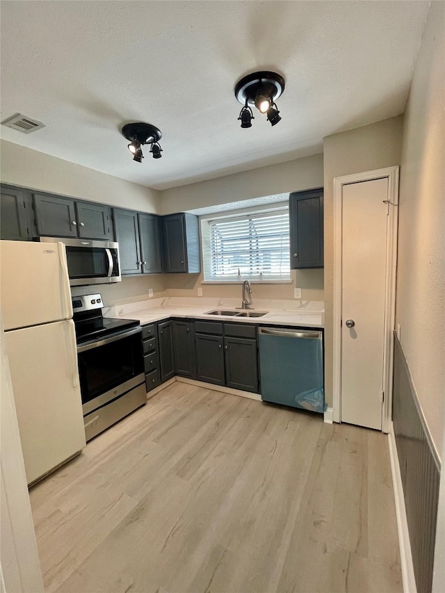 4748 Old Bent Tree Ln Unit 1104, Dallas, TX 75287 - kitchen featuring appliances with stainless steel finishes, a sink, light countertops, light wood-style flooring, and a textured ceiling