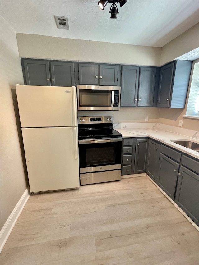 kitchen featuring gray cabinetry, light wood-type flooring, sink, and stainless steel appliances