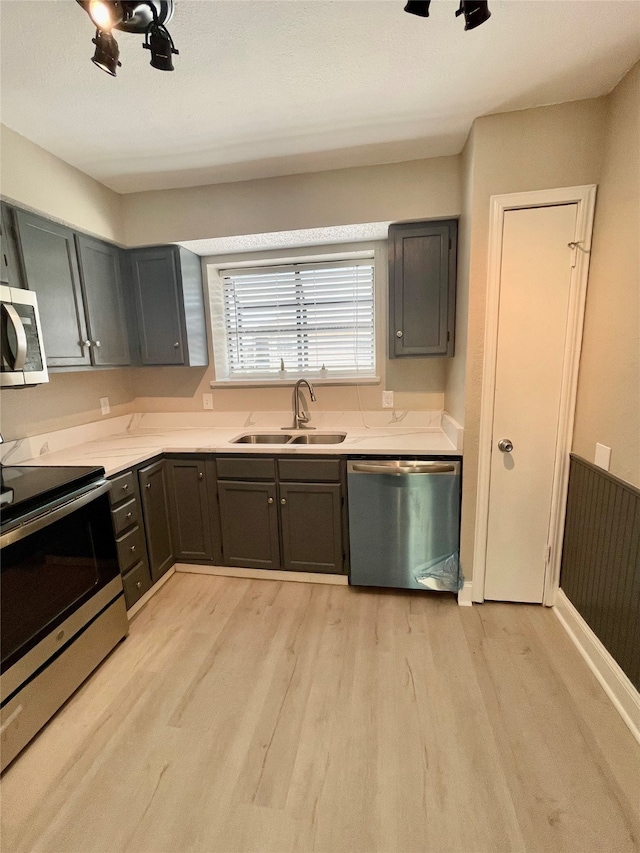 kitchen with light wood-type flooring, appliances with stainless steel finishes, and sink