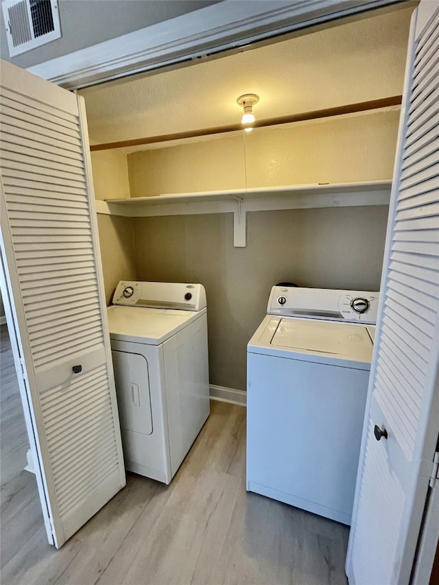 laundry room with washing machine and dryer and light wood-type flooring