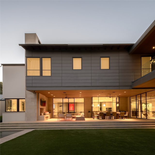 back house at dusk featuring an outdoor hangout area and a yard