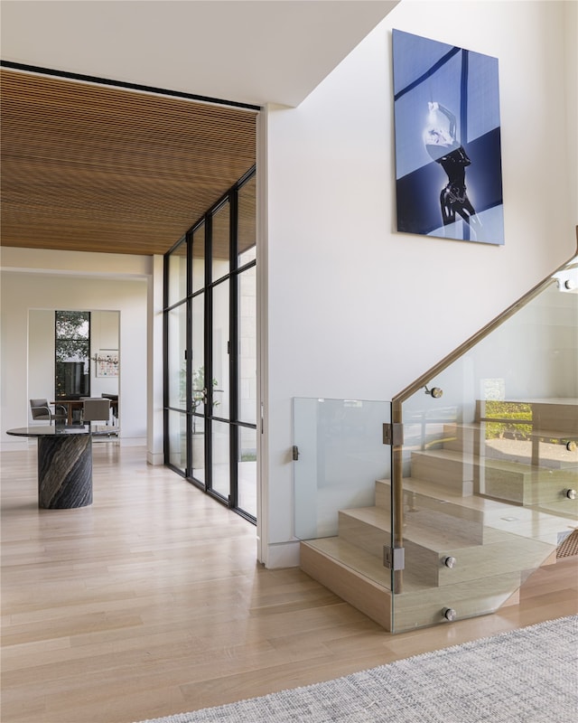 staircase featuring plenty of natural light, wood-type flooring, and floor to ceiling windows