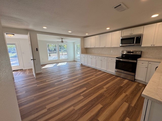 kitchen featuring white cabinets, appliances with stainless steel finishes, and dark wood-type flooring