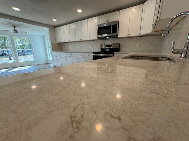 kitchen featuring white cabinets, sink, light stone counters, and stainless steel appliances