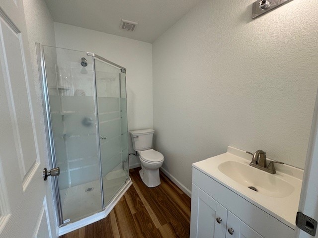 bathroom with hardwood / wood-style floors, vanity, toilet, and an enclosed shower