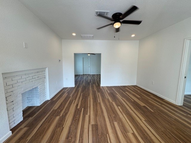 unfurnished living room featuring a brick fireplace, dark hardwood / wood-style floors, and ceiling fan