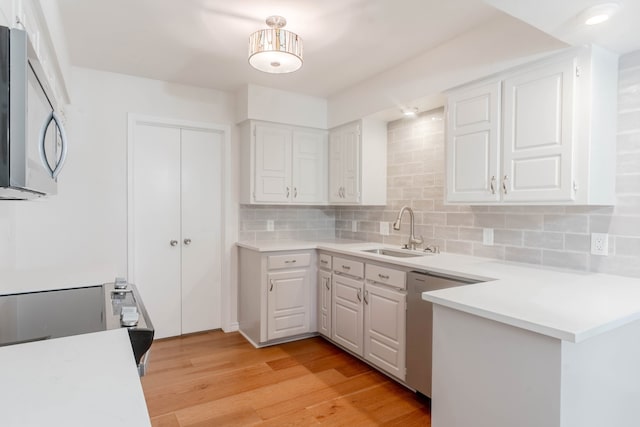 kitchen with sink, backsplash, stainless steel appliances, and white cabinets