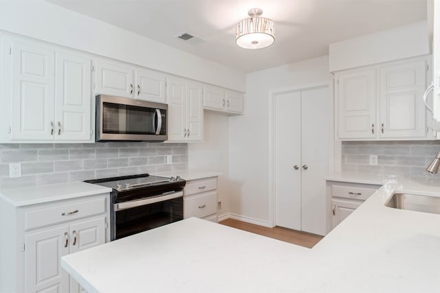 kitchen with white cabinetry, appliances with stainless steel finishes, and tasteful backsplash