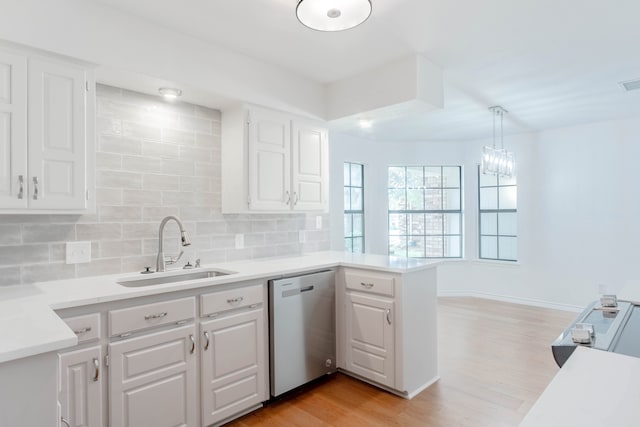 kitchen with decorative light fixtures, white cabinetry, sink, stainless steel dishwasher, and kitchen peninsula