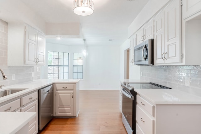 kitchen with white cabinetry, stainless steel appliances, kitchen peninsula, and sink