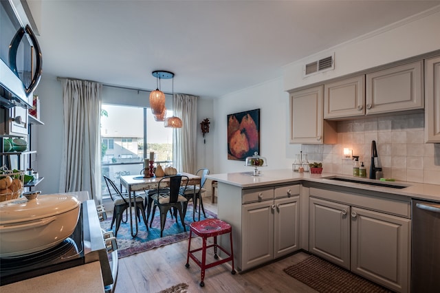 kitchen with kitchen peninsula, stainless steel appliances, sink, and light wood-type flooring