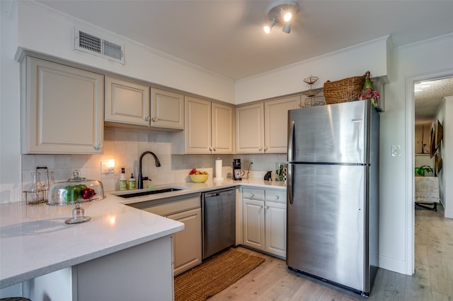 kitchen with stainless steel appliances, decorative backsplash, sink, crown molding, and light wood-type flooring