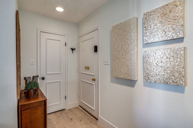 doorway featuring a textured ceiling and light hardwood / wood-style flooring