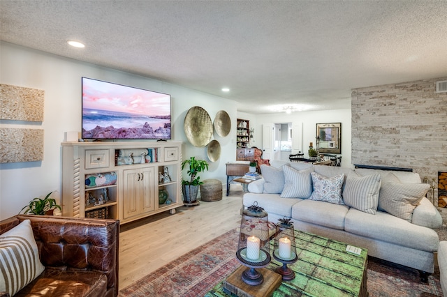 living room featuring a textured ceiling, light hardwood / wood-style floors, and a fireplace