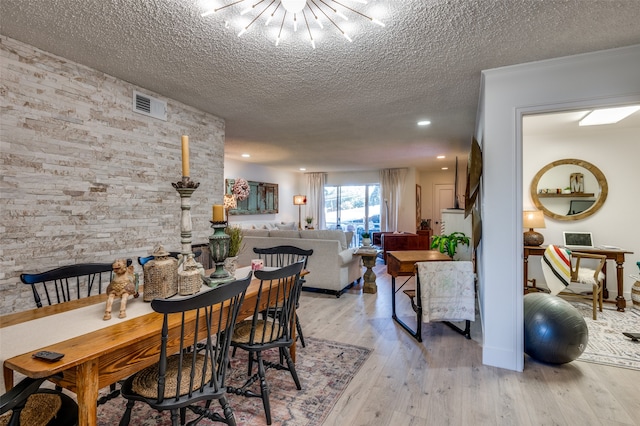 dining area with light hardwood / wood-style floors and a textured ceiling