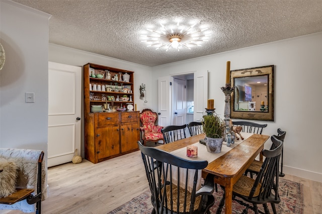 dining area featuring a textured ceiling, a notable chandelier, and light hardwood / wood-style floors