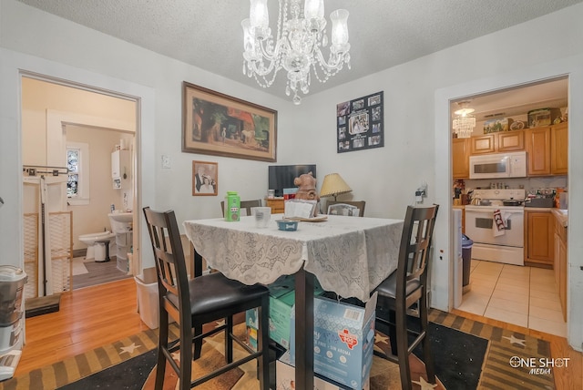 dining area featuring a chandelier, a textured ceiling, and light hardwood / wood-style floors