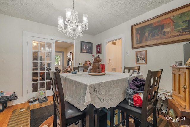 dining room featuring a textured ceiling, hardwood / wood-style flooring, and a notable chandelier