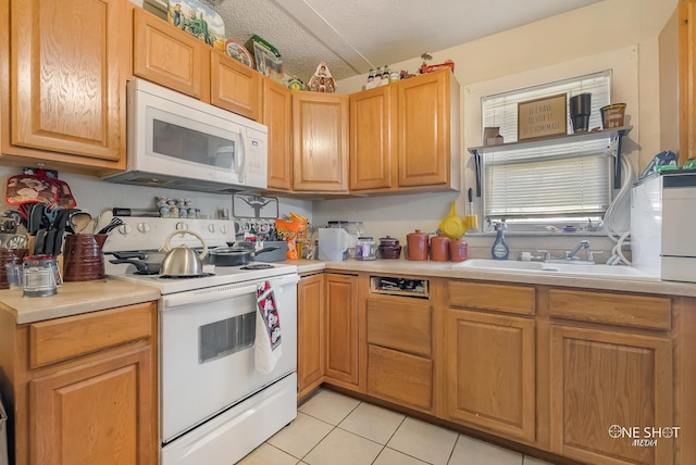 kitchen with a textured ceiling, sink, light tile patterned floors, and white appliances