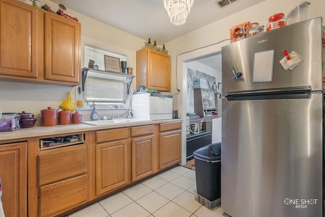 kitchen featuring stainless steel fridge, an inviting chandelier, light tile patterned floors, and sink