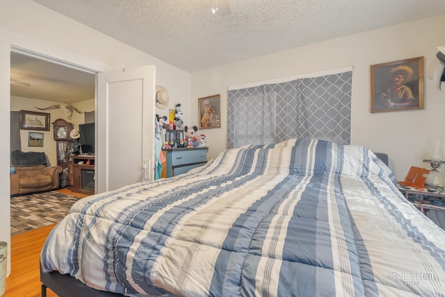 bedroom featuring ceiling fan, wood-type flooring, and a textured ceiling