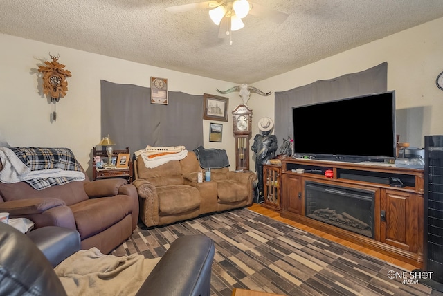 living room featuring ceiling fan, dark wood-type flooring, and a textured ceiling