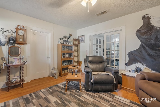 living area featuring hardwood / wood-style floors, a textured ceiling, and ceiling fan