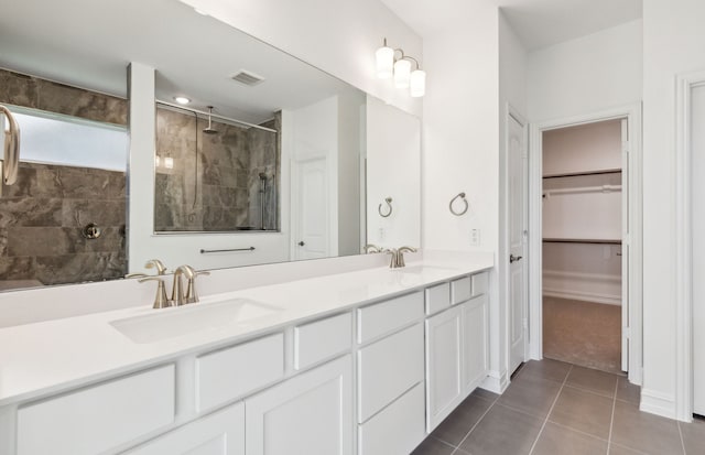 bathroom with tile patterned floors, vanity, and tiled shower