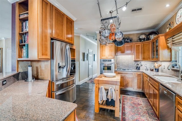 kitchen with stainless steel appliances, sink, ornamental molding, dark hardwood / wood-style floors, and light stone countertops