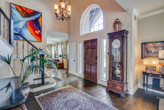 entrance foyer with dark hardwood / wood-style flooring, a high ceiling, crown molding, and an inviting chandelier