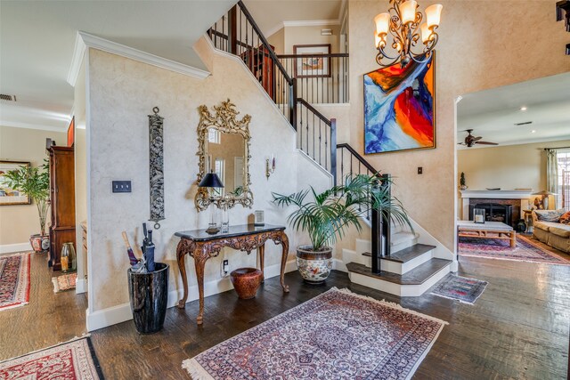 stairs with hardwood / wood-style floors, ceiling fan with notable chandelier, and crown molding