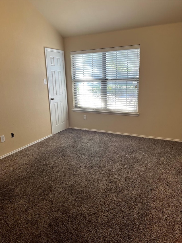 carpeted spare room featuring lofted ceiling